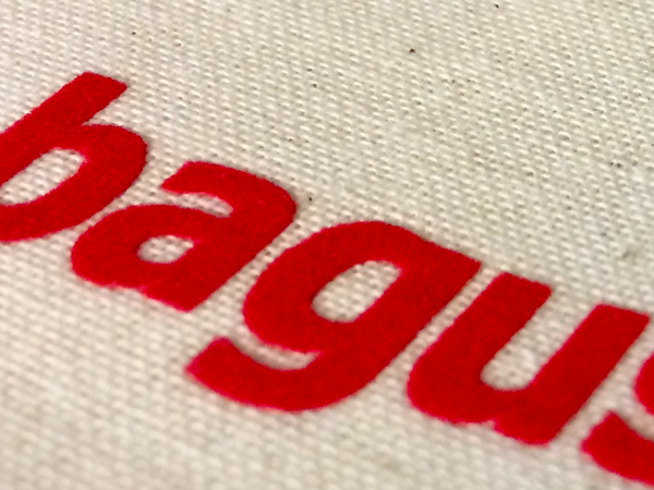 Detailaufnahme des roten baguse-Schriftzugs auf beigefarbenem Textilgewebe
